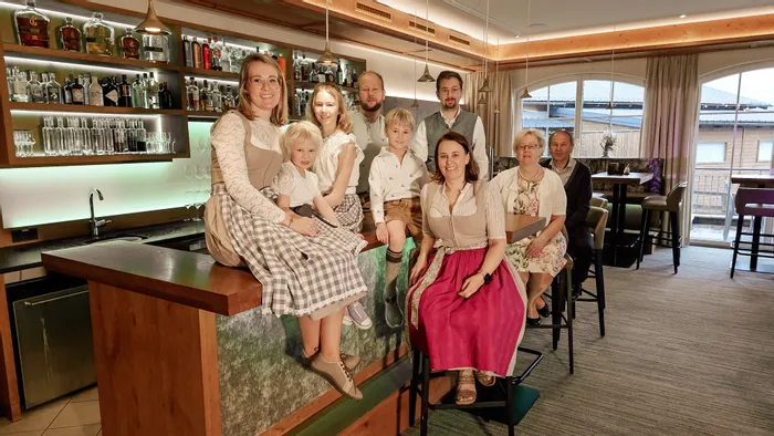 Familie in traditioneller Alpenkleidung posiert gemeinsam in modernem Barbereich